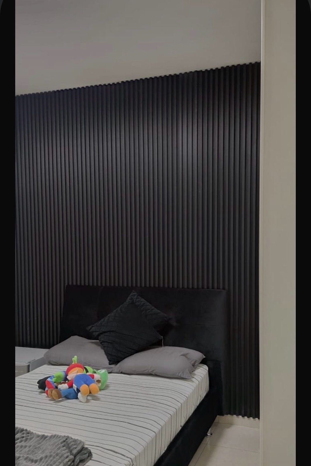 Full-height black fluted panelling behind a bed in a bedroom