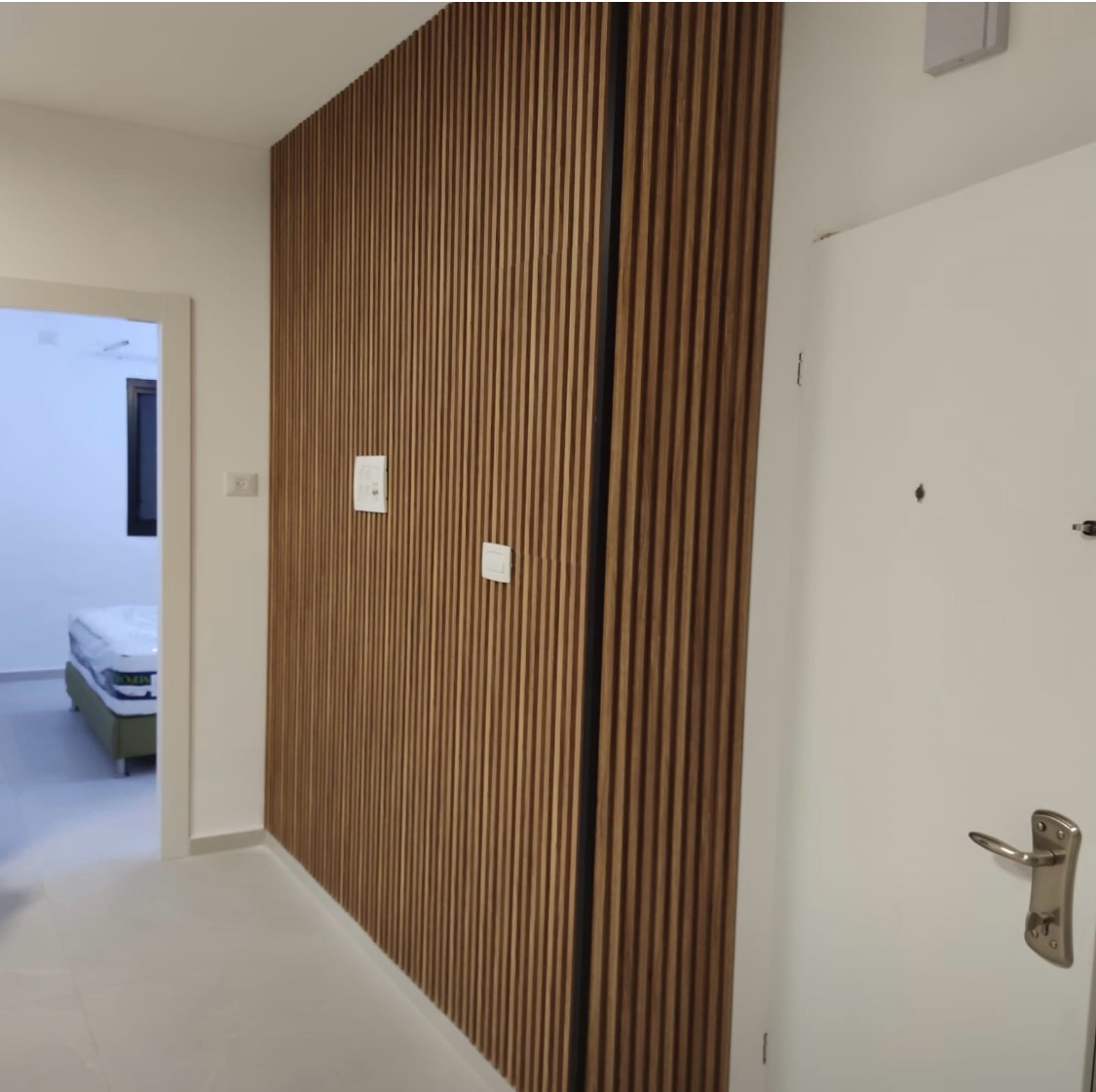 Walnut slat panelling running the length of an apartment hallway beside the front door